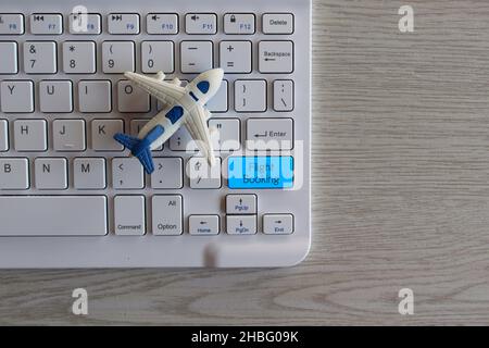 Biglietto aereo Online prenotazione volo concetto. Aereo giocattolo e tastiera con prenotazione di VOLO in formato testo. Foto Stock