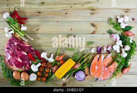 Manzo crudo, salmone e verdure su sfondo di legno Foto Stock