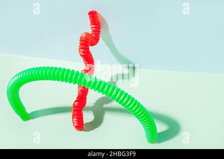 Il tubo pop curvo è appoggiato contro la parete. Vita morta moderna con giocattolo antistress. Foto Stock