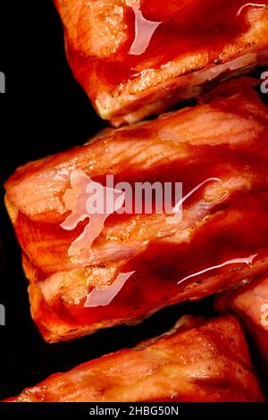 Macrosolato di sushi al salmone fritto condito con salsa unagi su sfondo nero Foto Stock