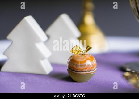 Figurine colorate di mela in onice su tavola viola con abeti bianchi sullo sfondo Foto Stock