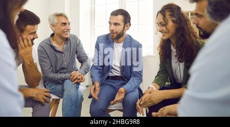 Business coach avere una conversazione con un gruppo di giovani felici e persone mature Foto Stock