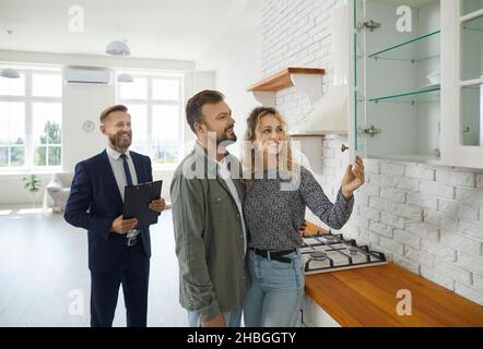 La coppia esamina i mobili in cucina mentre ispeziona la casa con agente immobiliare. Foto Stock