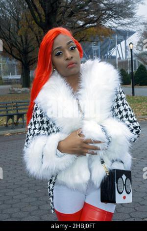 Ritratto posto di una bella signora con capelli arancioni e unghie lunghe. In un parco a Queens, New York City. Foto Stock