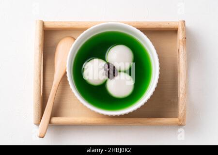 Vista dall'alto del matcha grande tangyuan (tang yuan) con zuppa di matcha dolce e pasta di fagioli rossi in una ciotola su sfondo bianco tavolo per cibo festival. Foto Stock