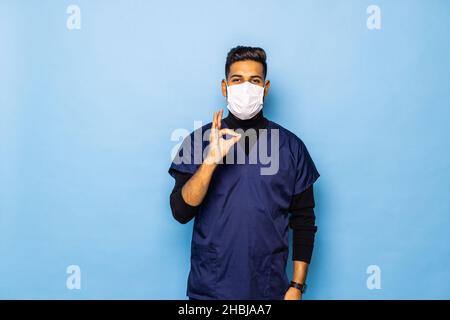 Foto di un bel uomo maturo medico in posa isolate su blu sullo sfondo della parete azienda pillole di vitamine che mostra bene gesto. Foto Stock