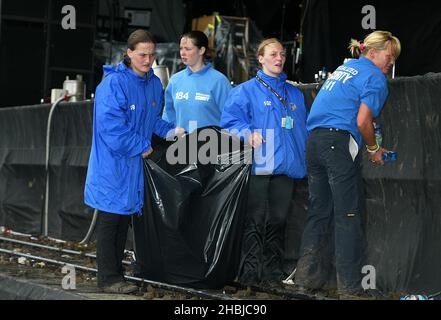 Sicurezza pulito mess da fango e fuochi d'artificio e bottiglie gettate a Rasmus il terzo giorno del 'il fine settimana di Carling: Reading Festival' a Reading, Inghilterra. Foto Stock