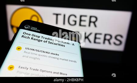 Telefono cellulare con sito web della società UP Fintech Holding Limited (Tiger Brokers) sullo schermo di fronte al logo. Mettere a fuoco sulla parte superiore sinistra del display del telefono. Foto Stock