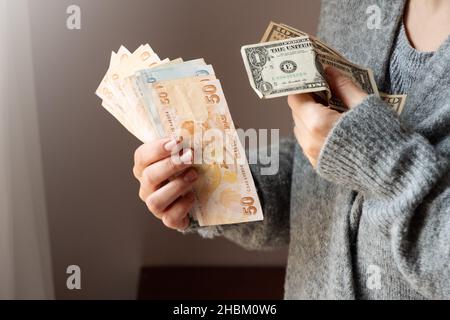 Banconote turche in lira e dollaro in mani femminili. La valuta cartacea della Turchia. Gli attuali lire turchi sono emessi dalla Banca Centrale della Repubblica di Turchia. Concetto di crisi finanziaria. Foto Stock