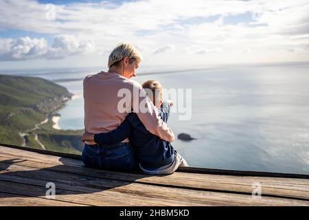 Madre e figlio di 3 anni si abbraccia e si gode la splendida vista sull'oceano, Portogallo Foto Stock