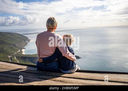 Madre e figlio di 3 anni si abbraccia e si gode la splendida vista sull'oceano, Portogallo Foto Stock