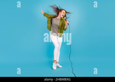 Foto a tutta lunghezza di affascinante donna attraente volare capelli cantare canzone mic star isolato su sfondo di colore blu pastello Foto Stock