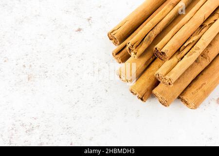 Primo piano di un mucchio di lunghi bastoncini di cannella su sfondo bianco macchiato con spazio copia. Vista ad angolo alto. Foto Stock