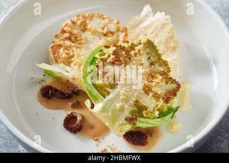 Alto angolo di gustose bistecche vegetariane di cavolfiore con salsa servita in stile piatto raffinato Foto Stock