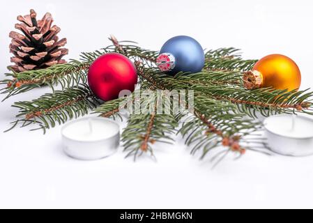 Natale e nuovo anno piatto laici: Ramo di abete verde, cono, rosso, blu e giallo palle, due candele e caramello caramella su sfondo bianco isolato. Foto Stock