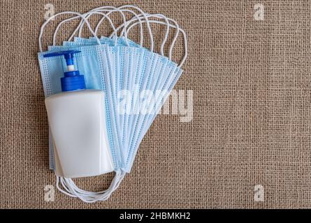 Maschere mediche e antisettiche su sfondo burlap. Foto Stock