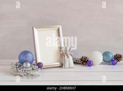 Decorazione di Natale, mockup cornice, ghirlanda blu su un tavolo bianco, spazio copia Foto Stock