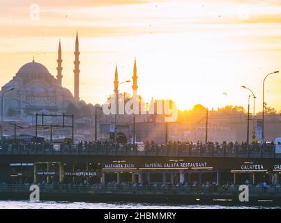 Ponte Galata con molti turisti, pescatore su di esso e ristoranti sotto di esso durante l'alba. Destinazione turistica affollata - Istanbul. Foto Stock