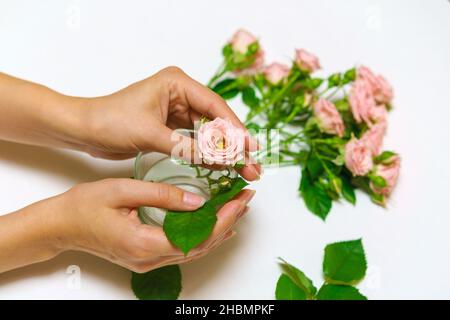 Primo piano della mano del fiorista donna che fa il bouquet delle rose rosa su un tavolo leggero. Bel bouquet carino per le vacanze delle donne. Il concetto del lavoro del fioraio nel negozio. Foto Stock