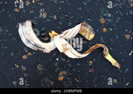 gettato via la buccia di banana sbucciata su via di tarmac scuro Foto Stock