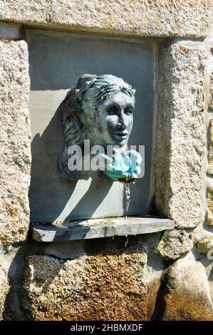 Faccia e le mani a tazza l'acqua caratteristica in una nicchia di pietra di granito a Abbey Gardens Tresco, Isole di Scilly, Cornovaglia Foto Stock