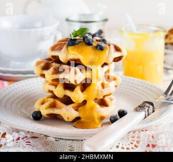 Waffle belgi al limone Kurd e mirtilli. Stile rustico. Messa a fuoco selettiva. Foto Stock