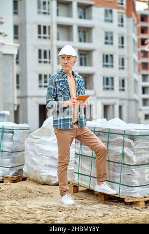 Uomo in piedi in cantiere guardando da parte Foto Stock