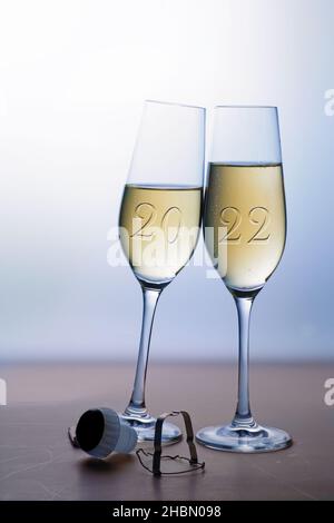 Due bicchieri da champagne con tostatura di Capodanno 2022, concetto di amore e vacanza, sfondo grigio blu con spazio copia, focus selezionato Foto Stock