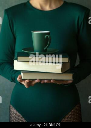 Mani che tengono pochi libri e una tazza di caffè Foto Stock
