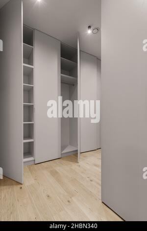 Nuovi ripiani armadio moderni vuoti con finiture in materiale grigio e porte aperte. Foto Stock