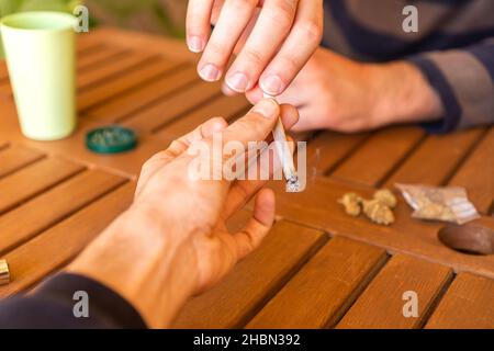 Persona non riconosciuta che passa una marijuana comune al suo amico durante una festa. Foto Stock
