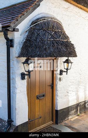 Una porta cottage con un piccolo portico di paglia nel villaggio Exmoor di Porlock, Somerset UK Foto Stock