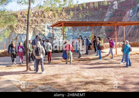 Huelva, Spagna - 18 dicembre 2021:un gruppo di turisti con la guida che visita la miniera a cielo aperto di Peña de Hierro a Nerva. Indossano una protec Foto Stock