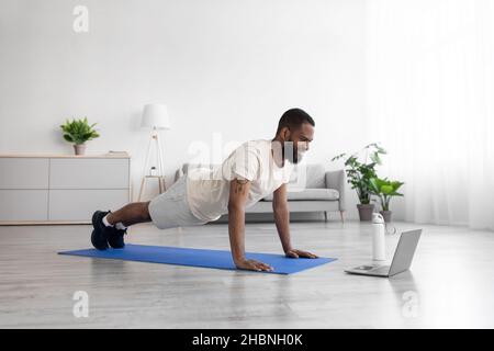 Sorridente sportivo nero con bearded in abiti bianchi fa asse e guarda il video Foto Stock