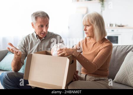 Dispiaciuti Senior Couple disimballaggio scatola di cartone a casa Foto Stock