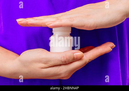 Le mani femminili tengono una bottiglia bianca di plastica con la medicina o le vitamine Foto Stock