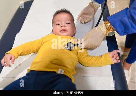 Pediatra che usa lo stetoscopio per ascoltare la respirazione di un bambino di razza mista di 5 mesi presso l'ufficio medico per un controllo di routine e un esame fisico Foto Stock