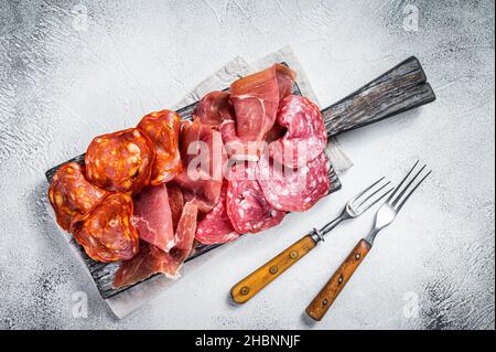 Antipasti di carne assortiti - salame, jamon, salsicce di choriso. Sfondo bianco. Vista dall'alto Foto Stock