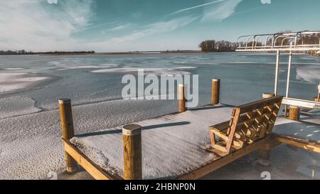 Prendi posto sulla panchina e goditi la vista della ghiacciata terra invernale. Il lago Winneconne è ghiacciato con la neve fresca sbarcare il giorno prima. Dicembre 2021 Foto Stock