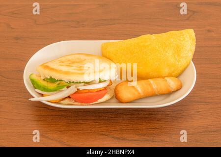 Vassoio piccolo con antipasti venezuelani, arepa al pomodoro, cipolla alla banana e avocado, tequeño ripieno di formaggio fresco e farina di mais empanada Foto Stock