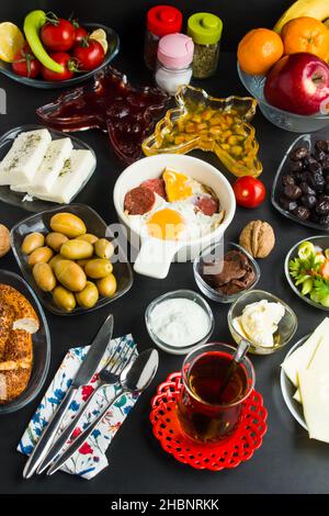 Colazione tradizionale turca sulla superficie nera. Salsiccia e uova al centro della cornice. Vista dall'alto. Foto Stock