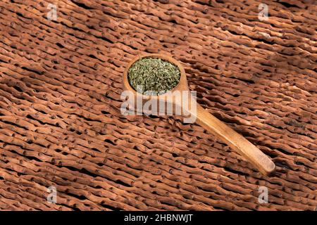 Artemisia draconculus - foglie di dragoncello organico essiccato in cucchiaio di legno Foto Stock