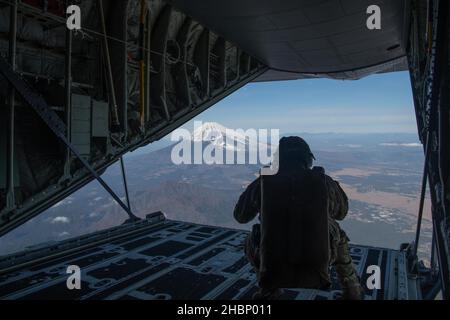 Personale dell'aeronautica degli Stati Uniti. SGT. Jordan Silversmith, 36th Airlift Squadron istruttore loadmaster, Surveys la terra a sostegno di un'alta quota, bassa apertura (ALONE) paracadute salti alla Yokota Air base, Giappone, 17 dicembre 2021. U.S. Marines e uno specialista statunitense di sopravvivenza, evasione, resistenza ed evasione dell'aeronautica (SERE) hanno condotto un allenamento di salto di una settimana utilizzando l'aeronautica militare e gli aerei della marina. Oltre a consentire a Marines e Airmen di praticare insieme le procedure di salto, la formazione di interoperabilità permette agli equipaggi Yokota di praticare tattiche di volo e tempi di lancio dei pacchetti. (STATI UNITI Air Force foto di Airman 1st Cla Foto Stock