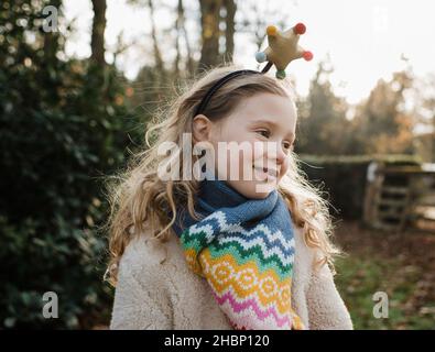 ragazza con un cerchietto natalizio all'aperto sotto il sole dorato Foto Stock