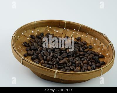 Chicchi di caffè di qualità in cesto di bambù isolato su sfondo bianco. Foto Stock