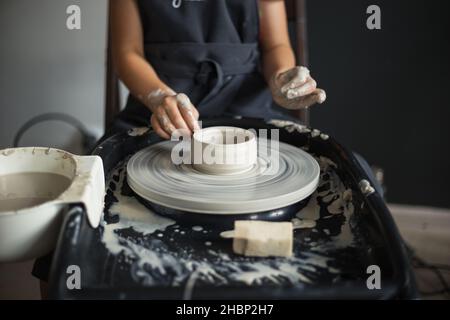 Le mani della ragazza che lavorano con l'argilla sulla ruota di un Potter in primo piano. La Foto Stock