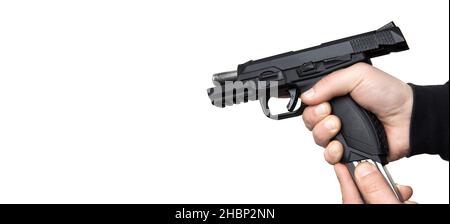 Un uomo in abiti scuri tiene una pistola nelle mani e la ricarica. Arma scaricata in mano. Foto Stock