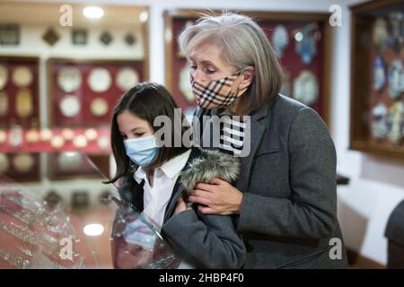 Tween studentessa e anziana tutor femminile in maschere facciali osservando la mostra in galleria d'arte Foto Stock