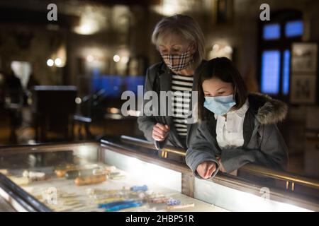 Tween studentessa e anziana tutor femminile in maschere facciali osservando la mostra in galleria d'arte Foto Stock