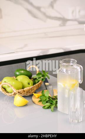 Bevanda rinfrescante a base di agrumi e menta in caraffa trasparente sul tavolo da cucina. Limone d'acqua rinvigorente ringiovanente Foto Stock